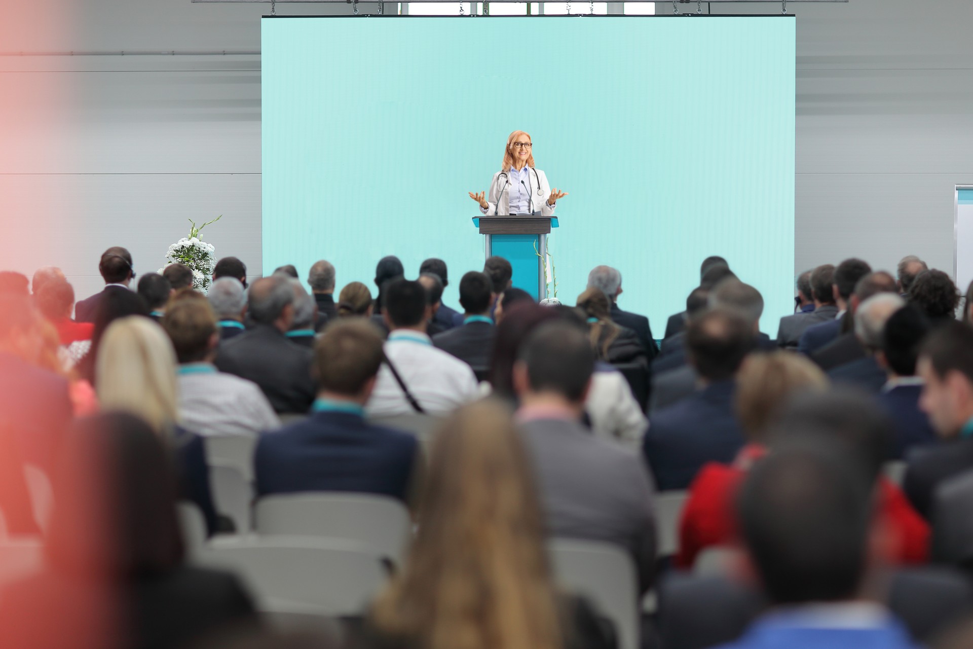 Female doctor giving a speech on a pedestal in front of an audience at a congress